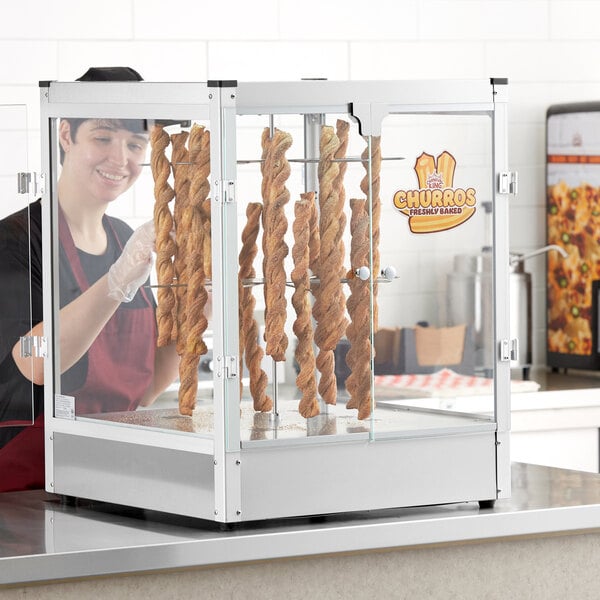 A woman standing behind a Carnival King churros display case.