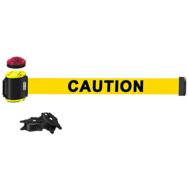 A black and yellow Banner Stakes wall mount barrier with yellow caution tape and a red light.