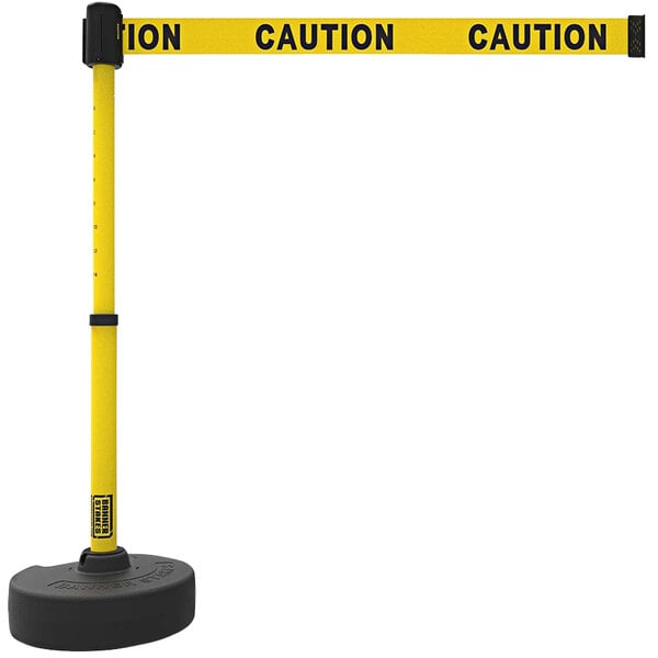 A yellow Banner Stakes PLUS retractable barrier with caution tape and a yellow caution sign.