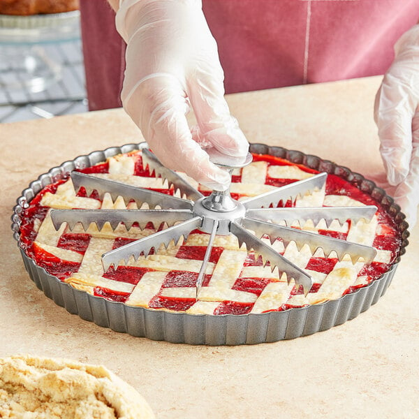 A person's gloved hand using a Choice 10-cut pie and cake marker to cut a pie.