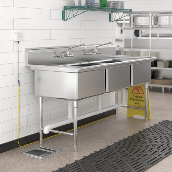 A stainless steel VersaTile flood sensor in a kitchen sink with faucets.