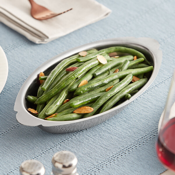 A oval stainless steel au gratin dish with green beans.
