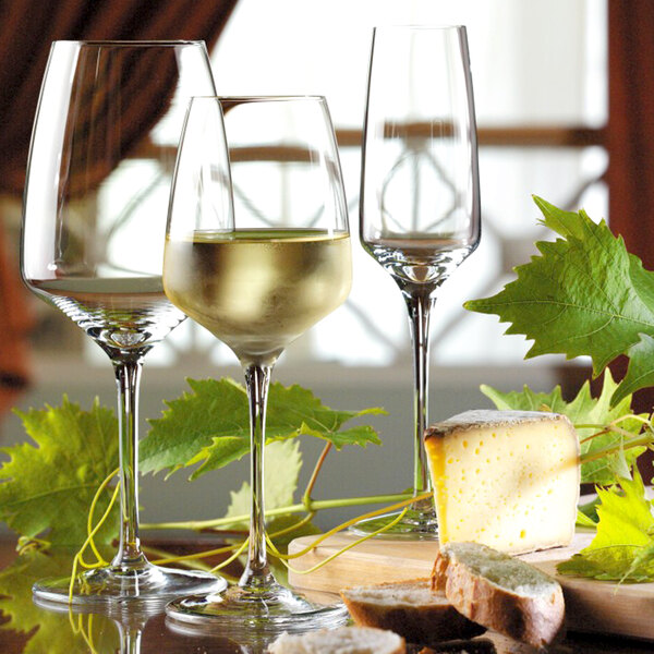 A table with Stolzle Bordeaux wine glasses, cheese, and bread.