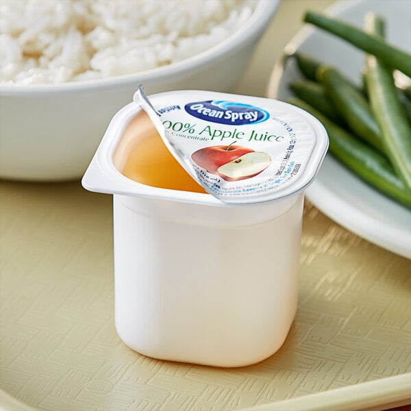 A white container of Ocean Spray apple juice on a plate of rice.