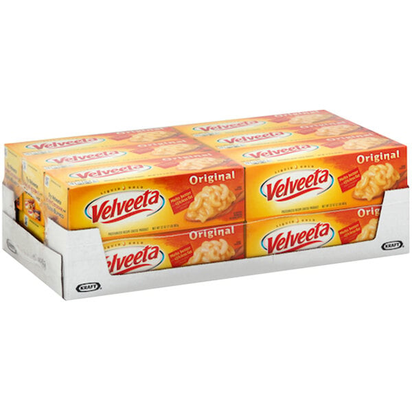 A stack of boxes of Kraft Velveeta Original American Cheese loaves on a grocery store shelf.