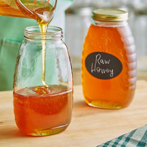 A person pouring honey into a Classic Queenline glass honey jar.