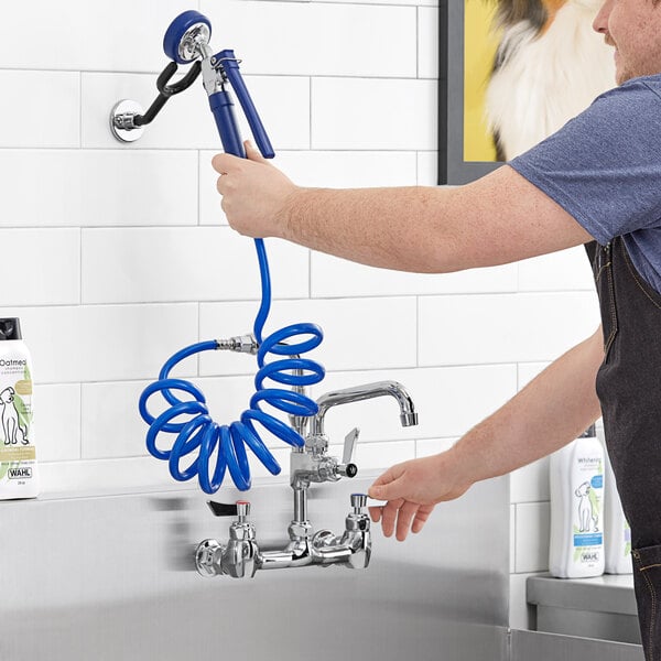 A man using a hose to open a Waterloo pet grooming faucet.