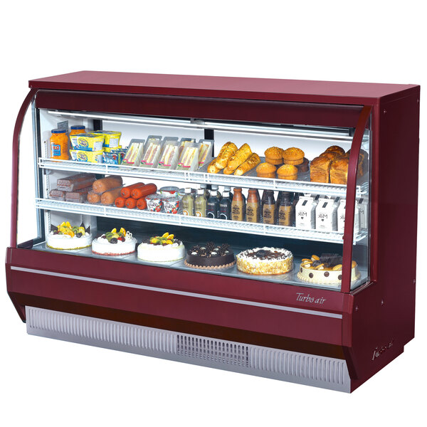 A red Turbo Air refrigerated deli case with curved glass and food on shelves.