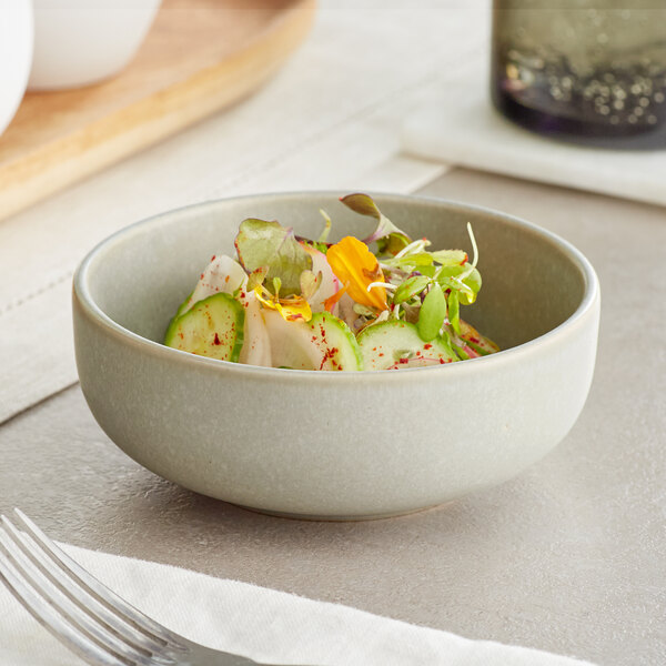 A white Acopa Pangea nappie bowl filled with salad on a table with a fork.
