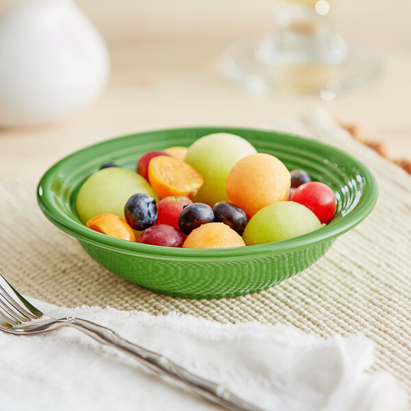 An Acopa Capri palm green stoneware bowl filled with fruit on a table.