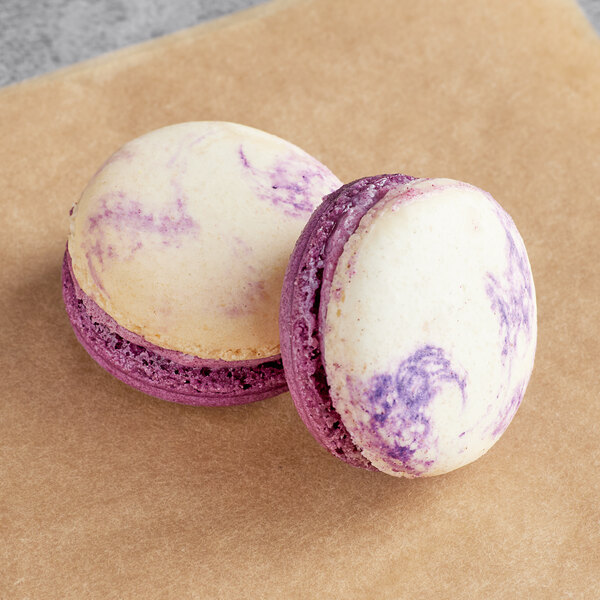 Two purple and white Ube White Chocolate macarons on a table.