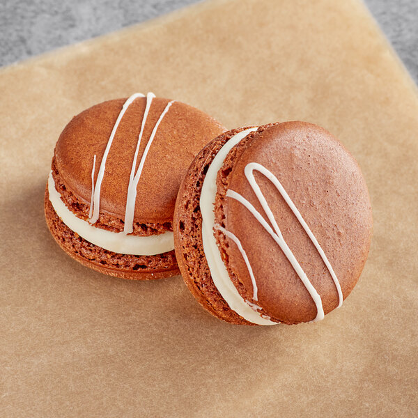 Two brown Macaron Centrale macarons with white frosting on them.