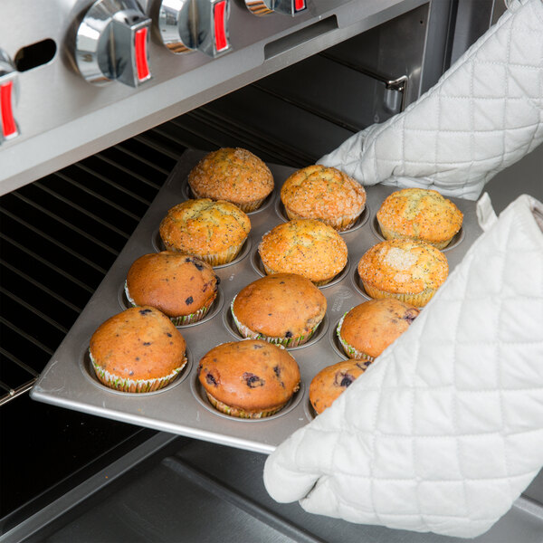 A person holding a Chicago Metallic jumbo crown muffin pan full of muffins.