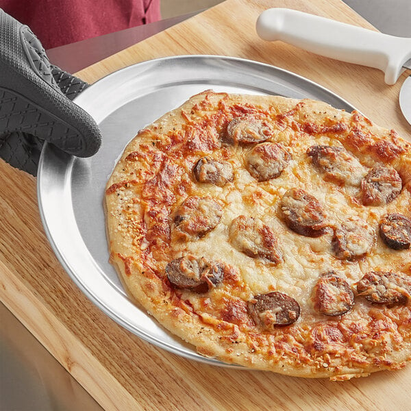 A pizza on a Choice aluminum wide rim pizza pan.
