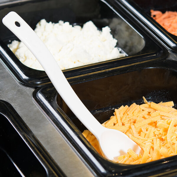 A white Cambro Camwear spoon in a tray of food on a salad bar counter.