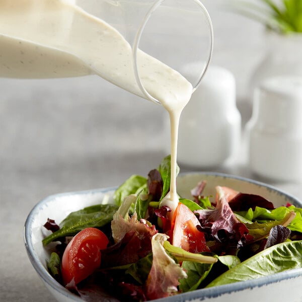A salad with AAK Select Recipe Ranch Dressing being poured over it.