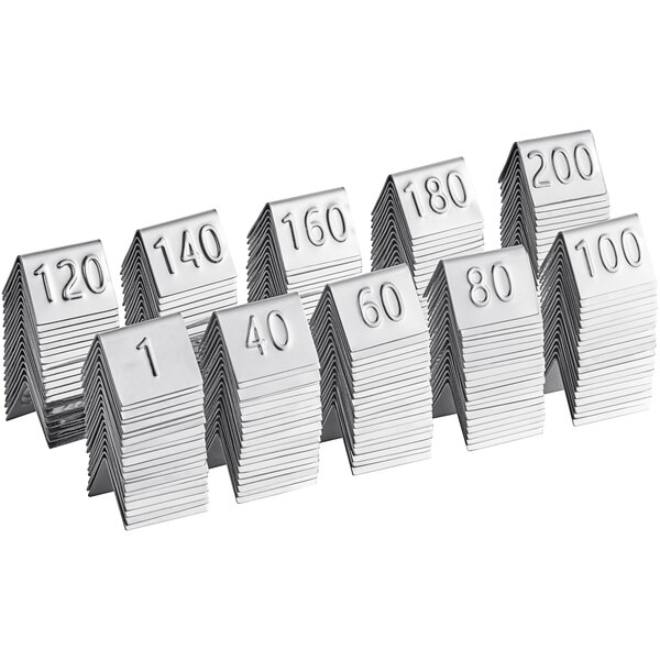 A row of American Metalcraft stainless steel number table tents with numbers on them.