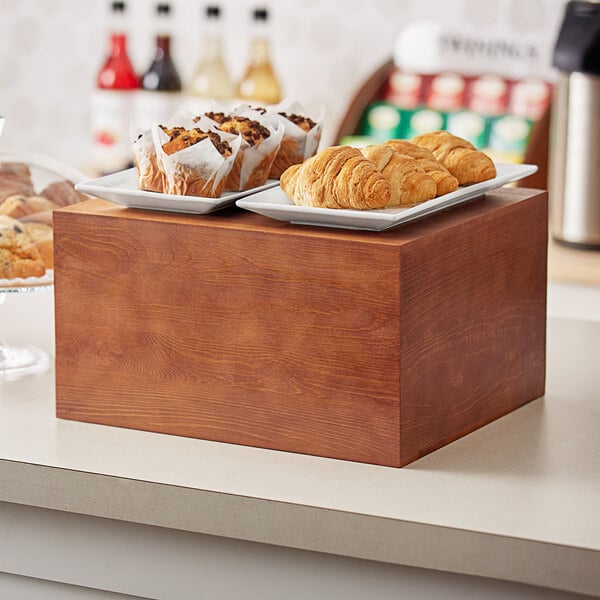 An Acopa wood display riser with pastries on it on a bakery counter.