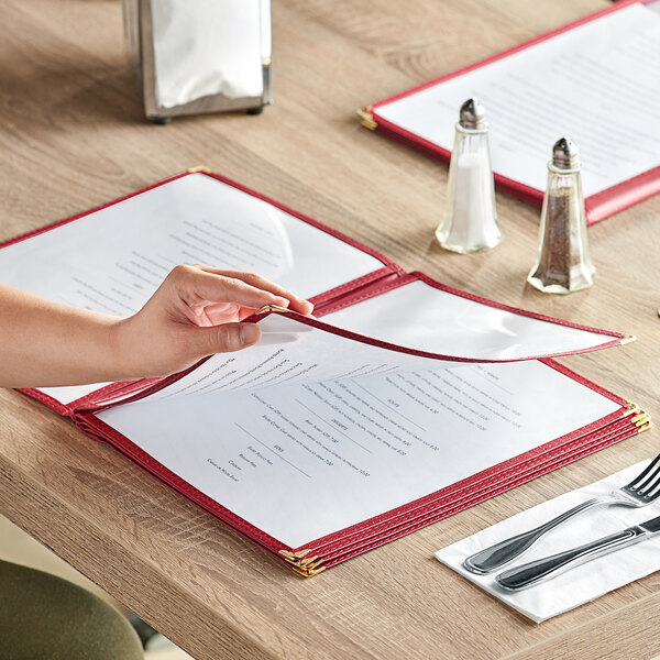 A person holding a burgundy Choice menu cover with a fork and knife inside.