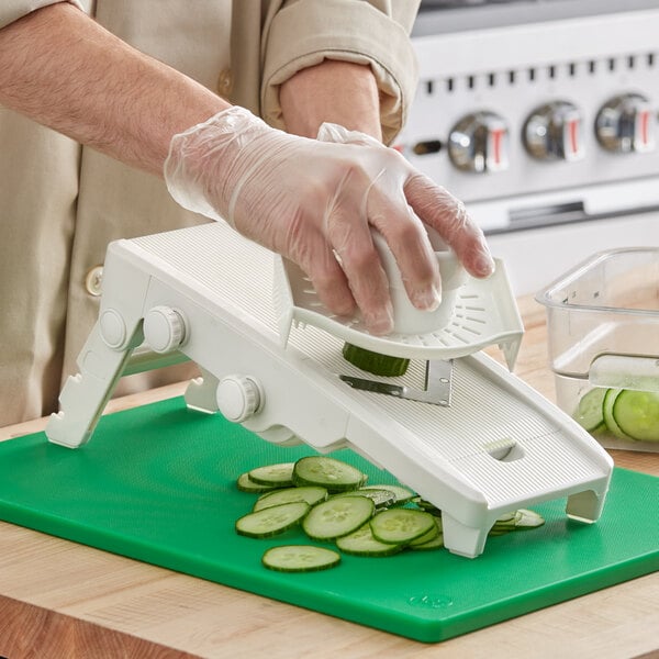A person using a Choice Plastic V-Shaped Mandoline to slice cucumbers.