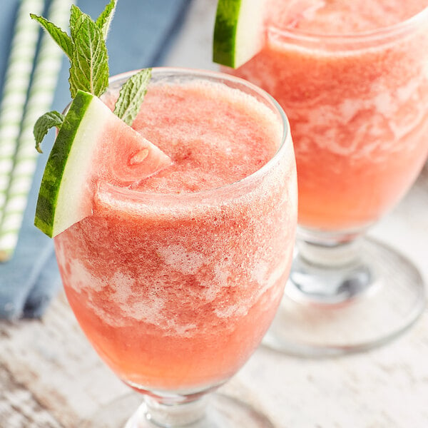 Two glasses of watermelon and mint drink with Pitaya Foods watermelon cubes on the rim.