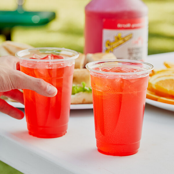 A hand holding a plastic cup with red Sqwincher Fruit Punch in it.