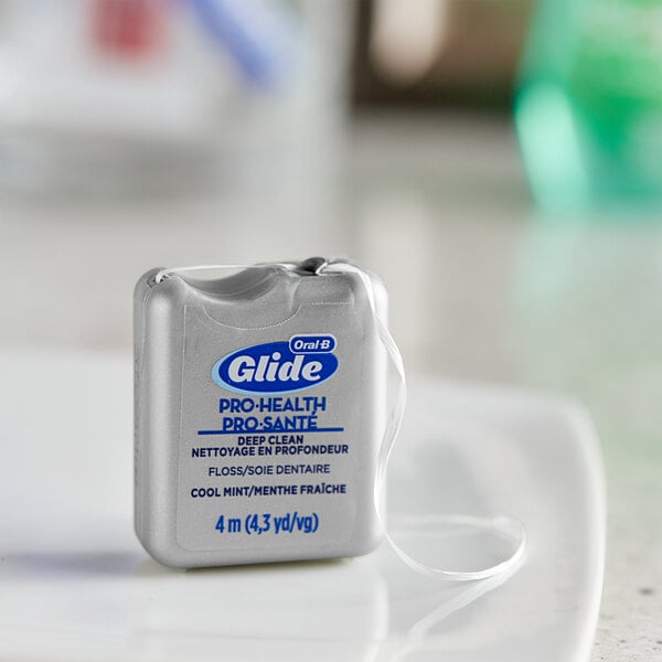 An Oral-B Glide Pro-Health dental floss on a white plate.