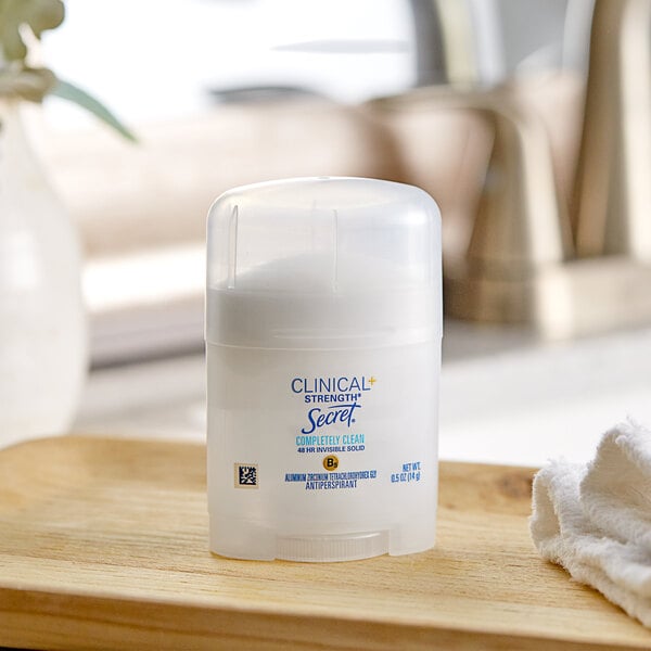 A white container of Secret Clinical Strength antiperspirant deodorant on a wooden tray.