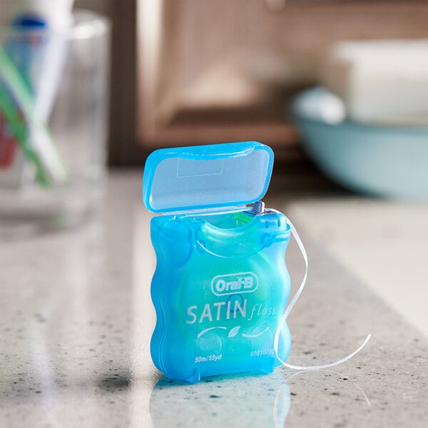 A blue plastic container of Oral-B Complete Mint Satin Dental Floss with white string inside.