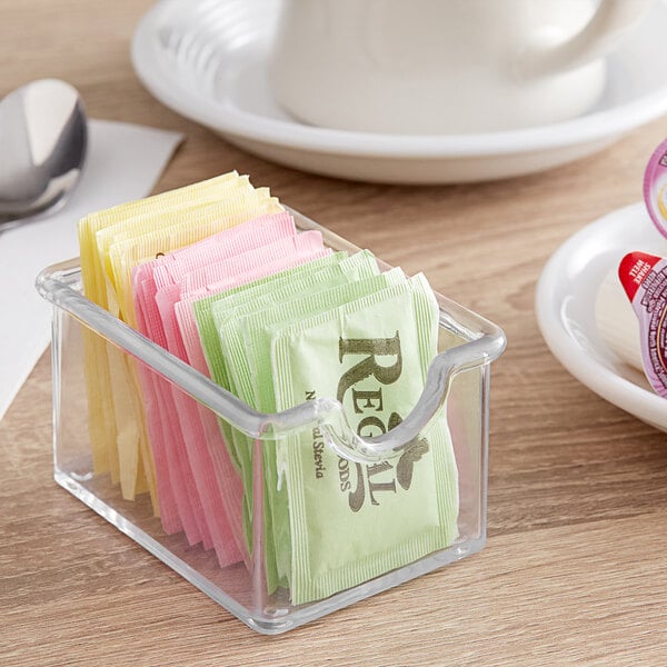A clear plastic container with sugar packets inside.