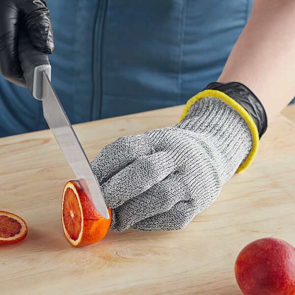 A person using Schraf cut-resistant gloves to cut an orange.