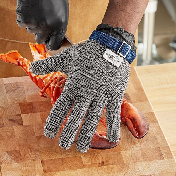 A person wearing Schraf chain mail gloves cutting a lobster.