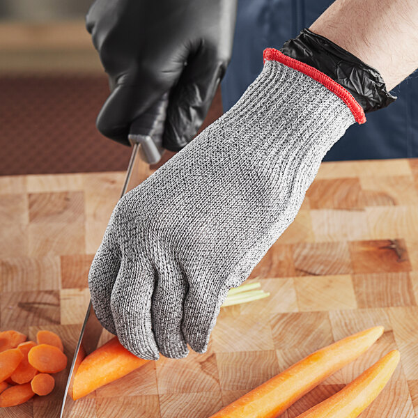 A person cutting a carrot with a Schraf gray cut-resistant glove.