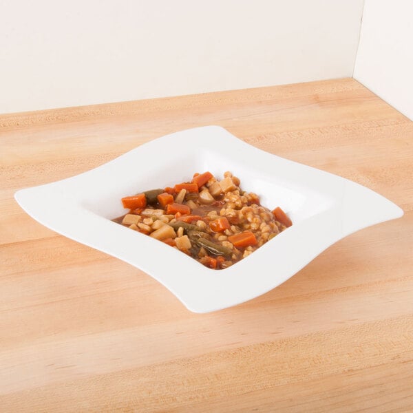 A white Fineline disposable plastic bowl filled with food on a table.