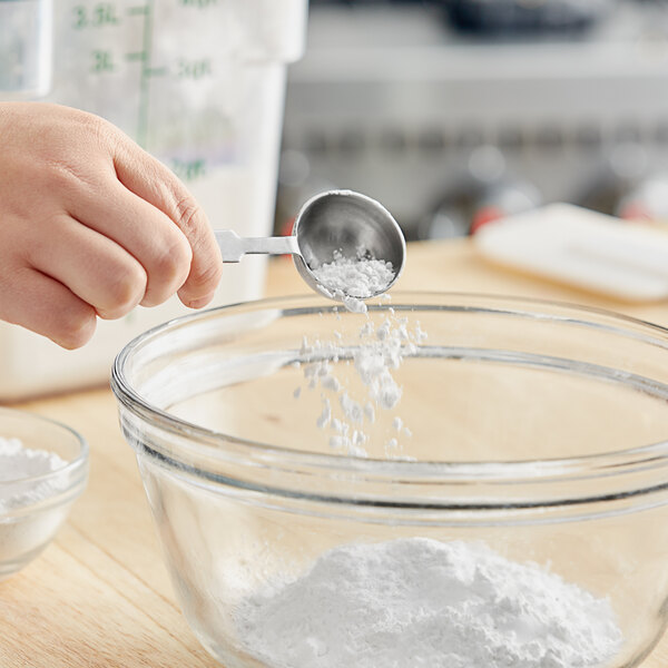 A hand pouring Double Acting Baking Powder into a bowl.