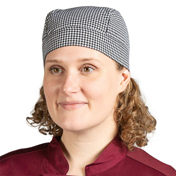 A woman smiling and wearing an Uncommon Chef houndstooth chef skull cap with ties.