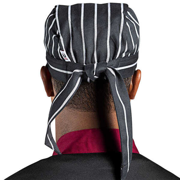 A Uncommon Chef chalk stripe chef skull cap with ties on a counter.