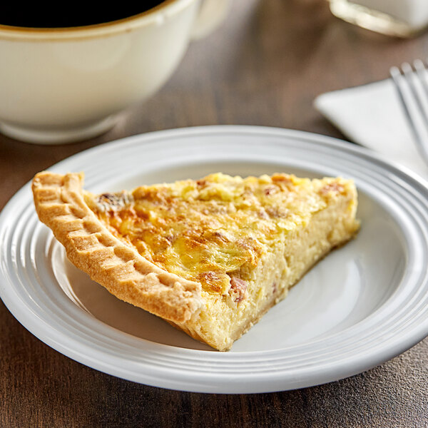 A slice of Country Chef Baked Lorraine Quiche on a plate next to a cup of coffee.