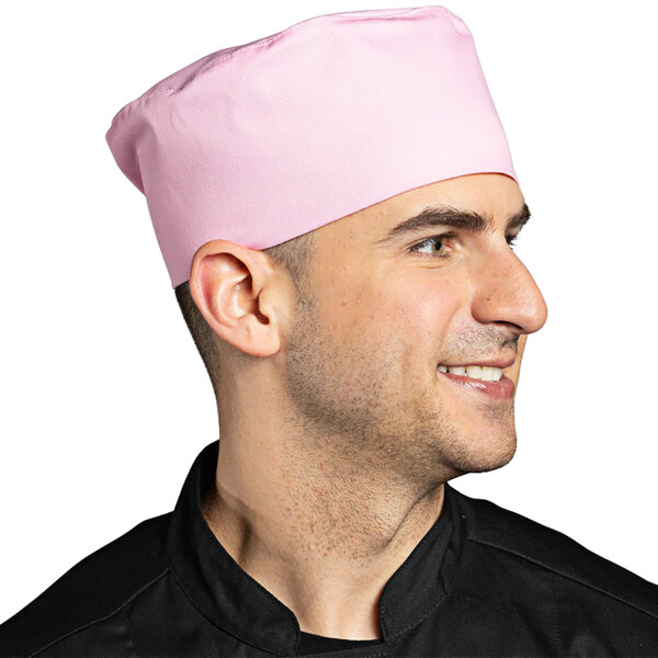 A man wearing a pink Uncommon Chef skull cap with a hook and loop closure in a professional kitchen.