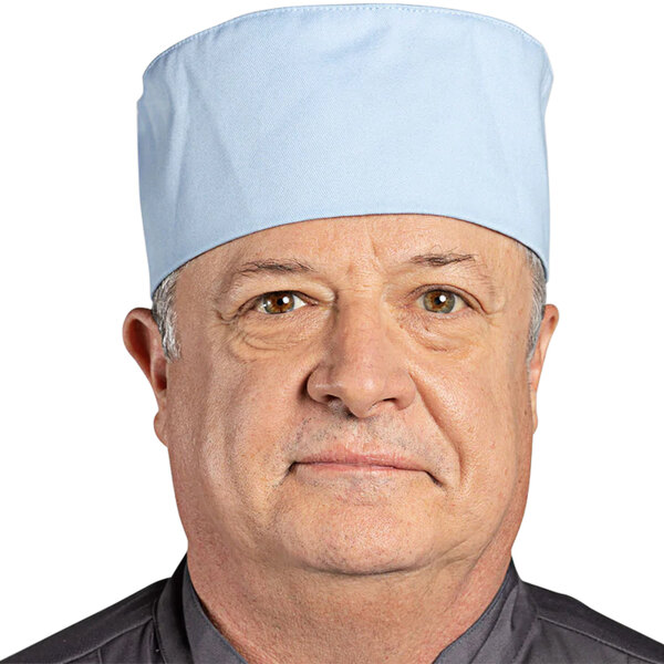 A man wearing a blue Uncommon Chef skull cap with hook and loop closure.
