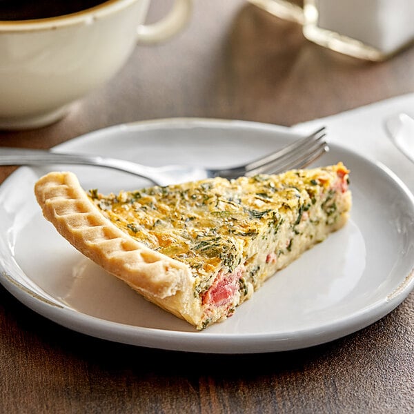 A slice of Country Chef spinach and tomato quiche on a plate with a cup of coffee.