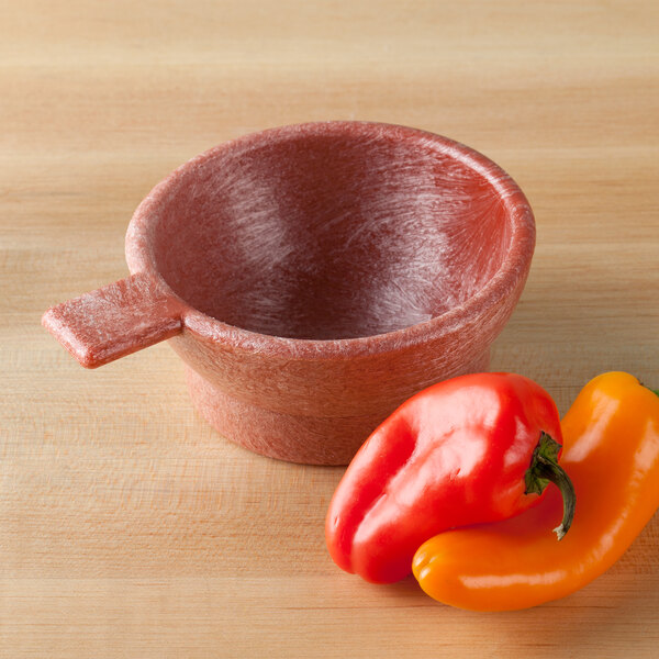 A HS Inc. paprika polyethylene bowl with a red lid on a table with bell peppers.