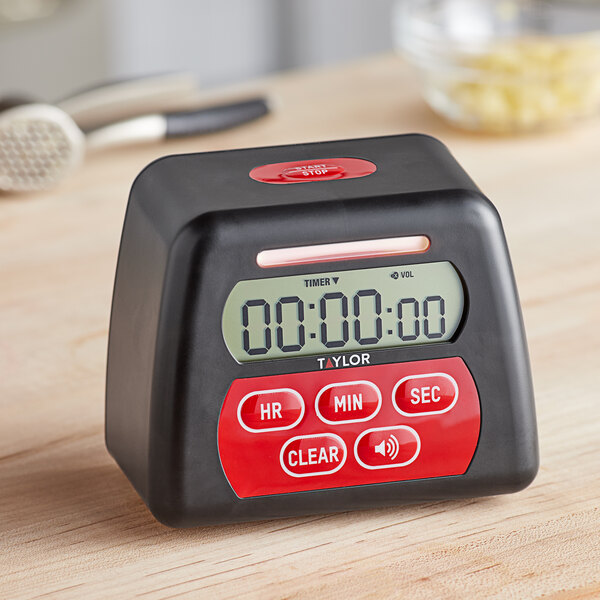 A black and red Taylor digital kitchen timer on a wooden table.