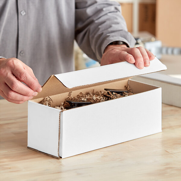 A person opening a Lavex white corrugated mailer box with a lid open.
