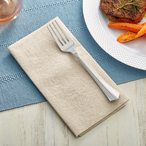 A fork on a Choice Touchstone natural linen-feel dinner napkin next to a plate of carrots.