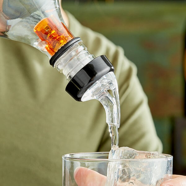 A person using a Choice 3-Ball Measured Liquor Pourer to pour a drink.