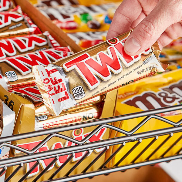 A person holding a TWIX chocolate cookie bar.