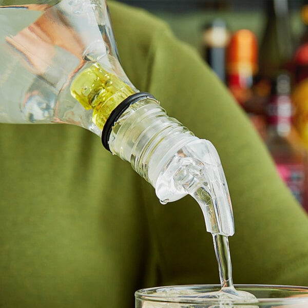 A person using a Choice 3-Ball Measured Liquor Pourer to pour liquid into a glass.