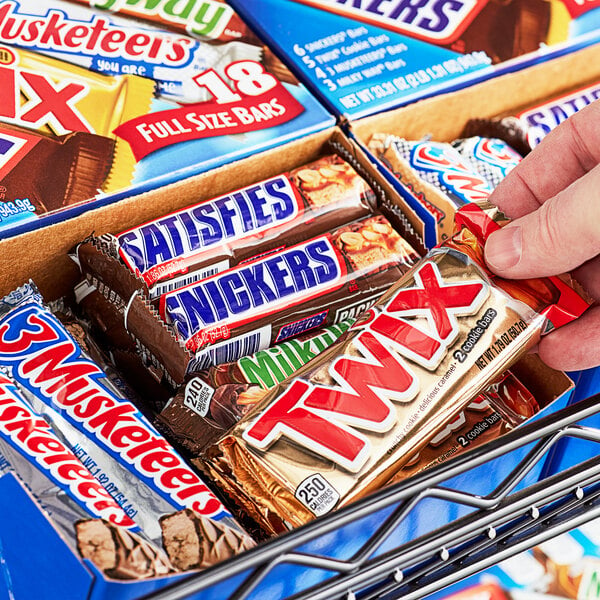 A hand holding a Mars Full Size Candy Bar from a box.