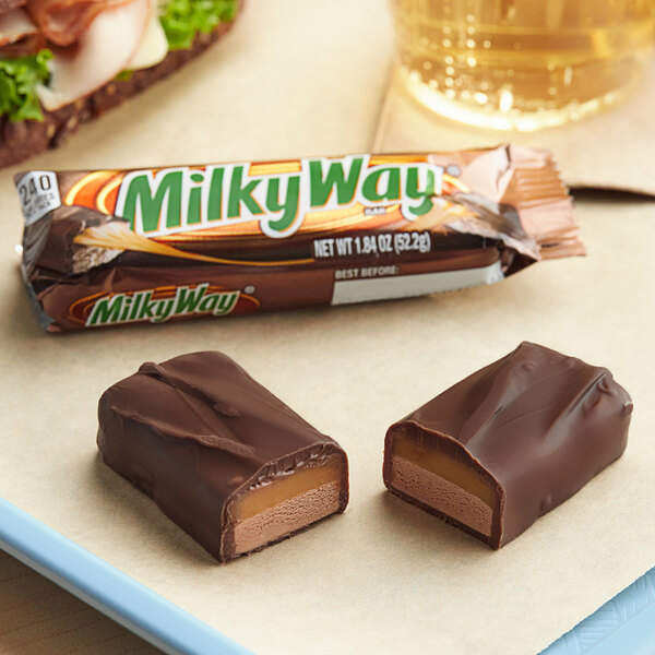 A close up of a MILKY WAY chocolate bar on a plate next to a drink.
